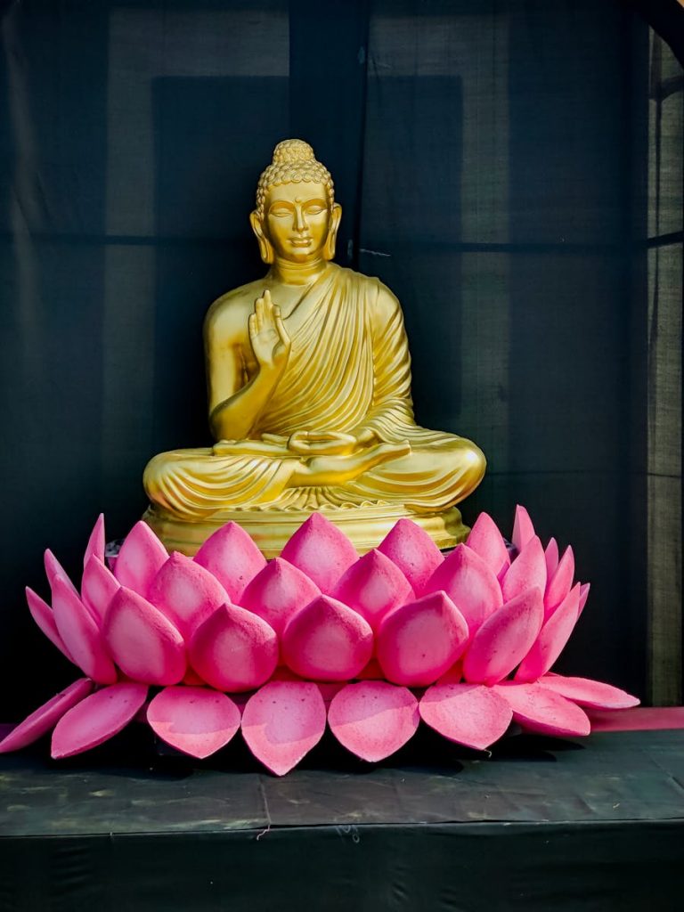 Statue of Buddha Sitting in front of Pink Petals